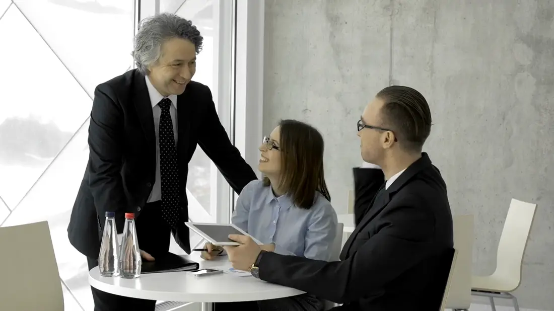 Gestor acolhe a equipe à mesa, todos sorrindo